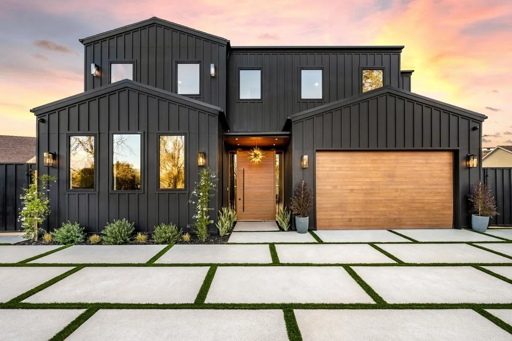 Cedar-tone flush garage door on a black board-and-batten house