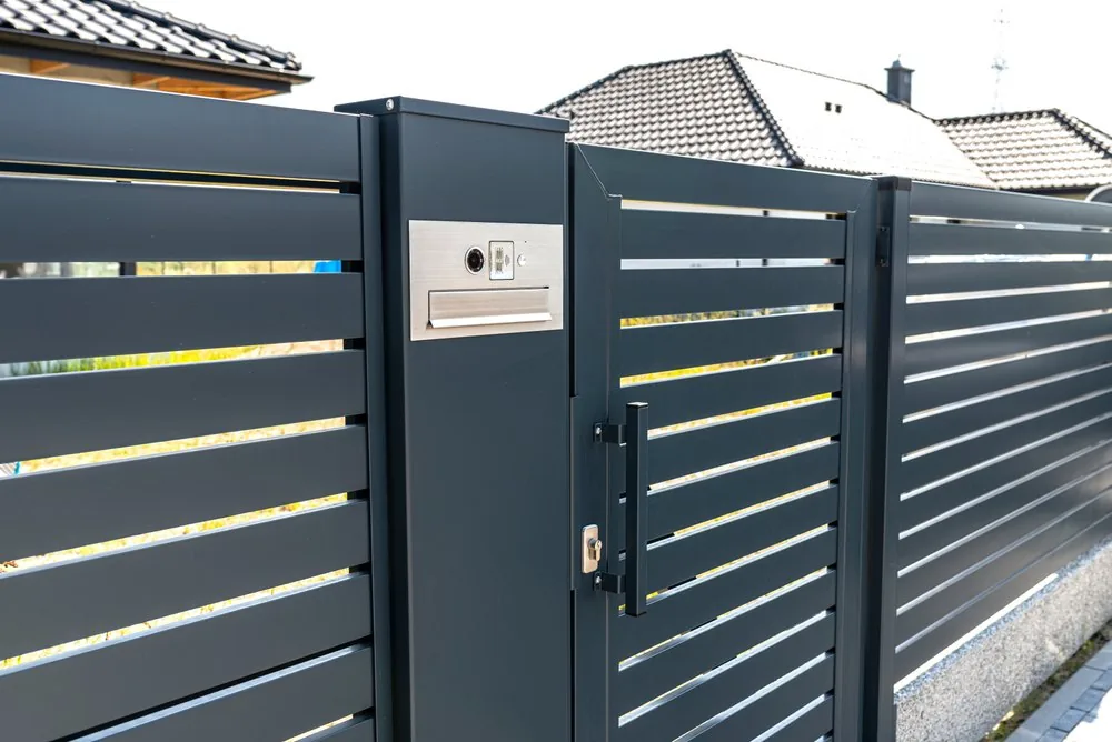 Charcoal horizontal-slat pedestrian gate with a built-in intercom and mailbox