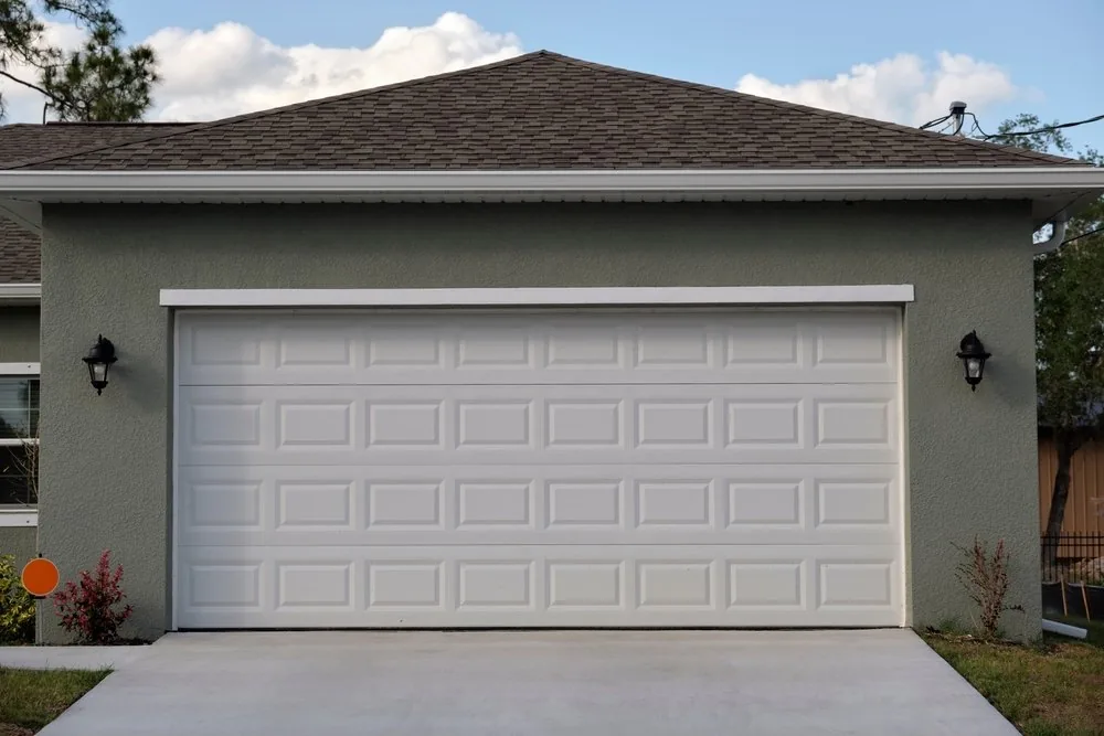 White raised-panel two-car garage door on a gray stucco garage
