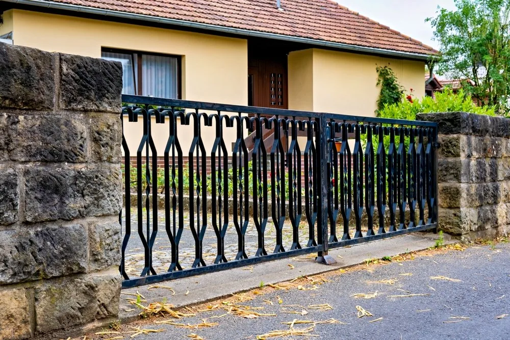 Ornamental black iron sliding gate between stone pillars